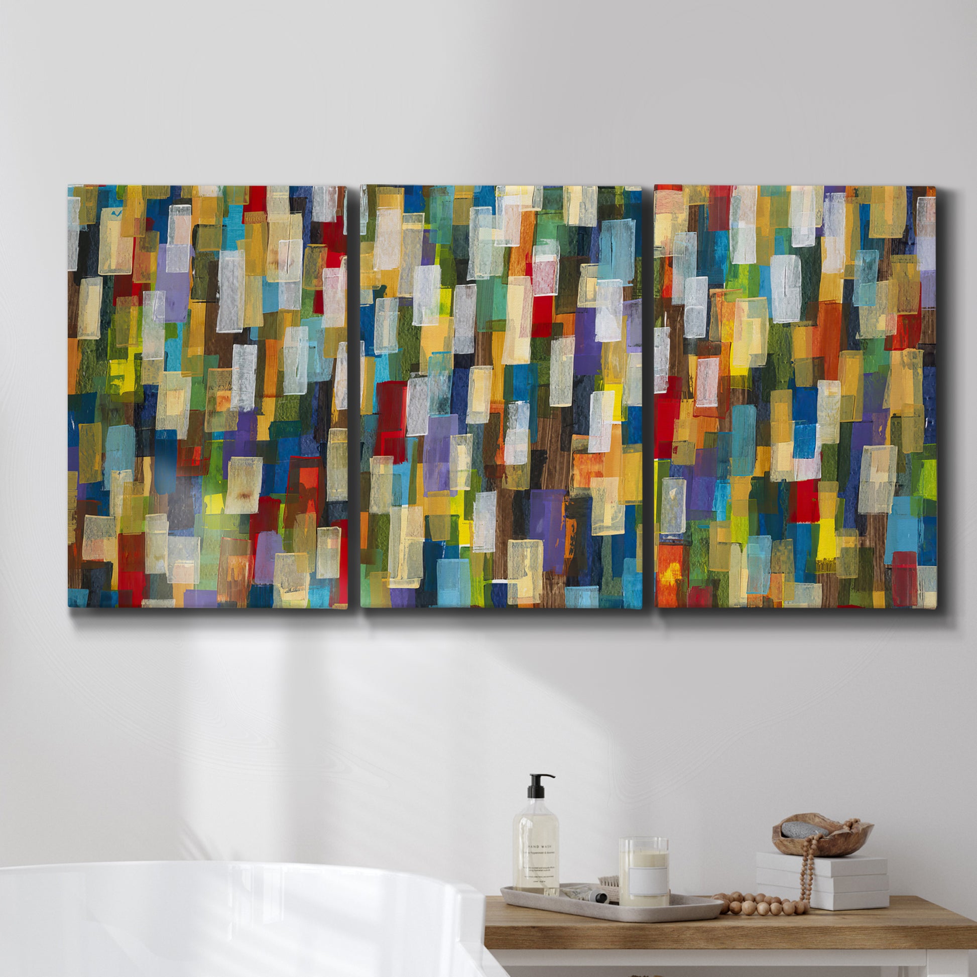 Three-panel canvas wall art featuring colorful confetti style abstraction, displayed in a bathroom above a bathtub.