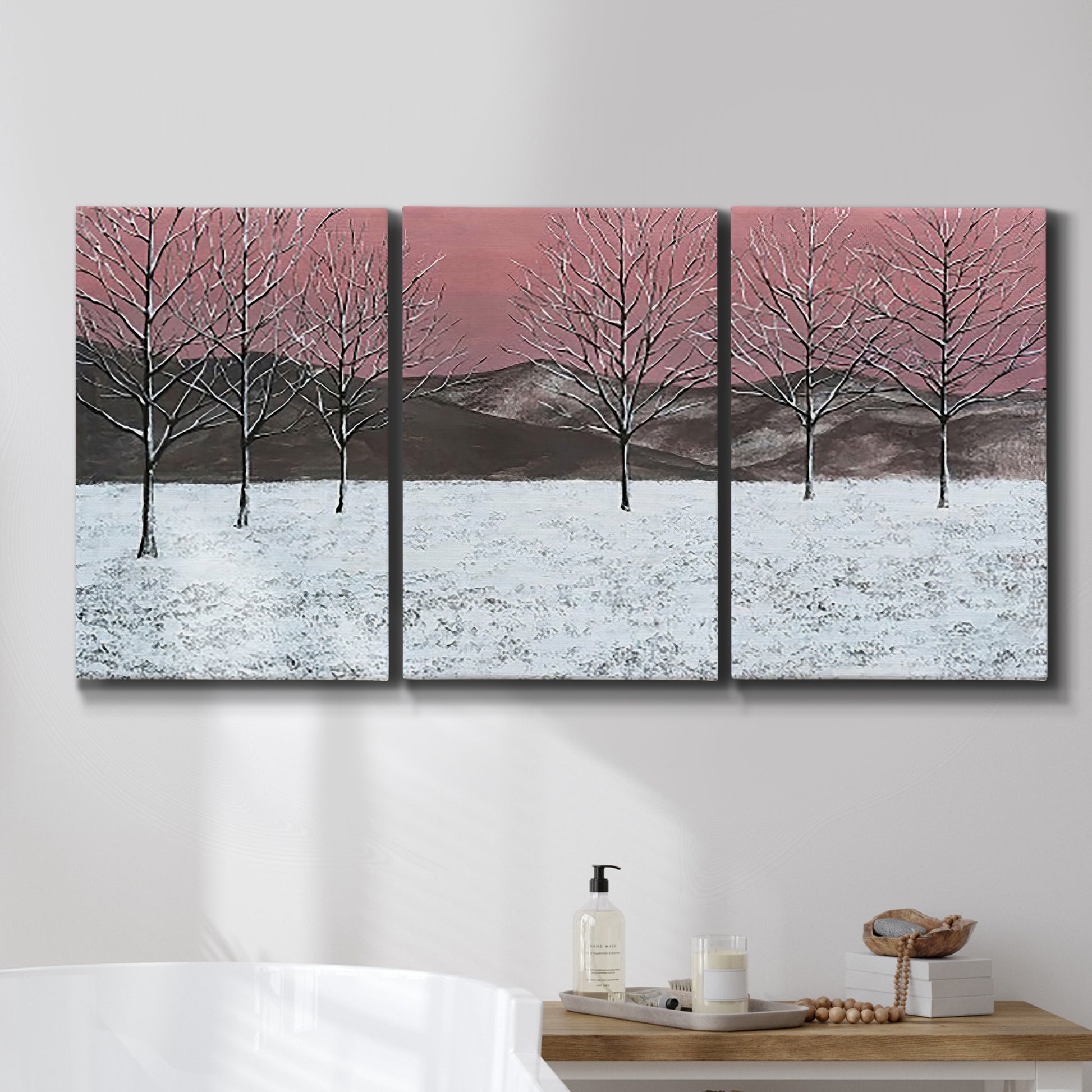 Three-panel canvas wall art featuring winter sunset snowfall landscape, displayed in a bathroom above a bathtub.