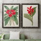 Set of two black barnwood framed canvas prints depicting a coordinated art pair of vivid tropical flowering plants rendered as antique botanical plate illustrations above a sofa in a modern living room.