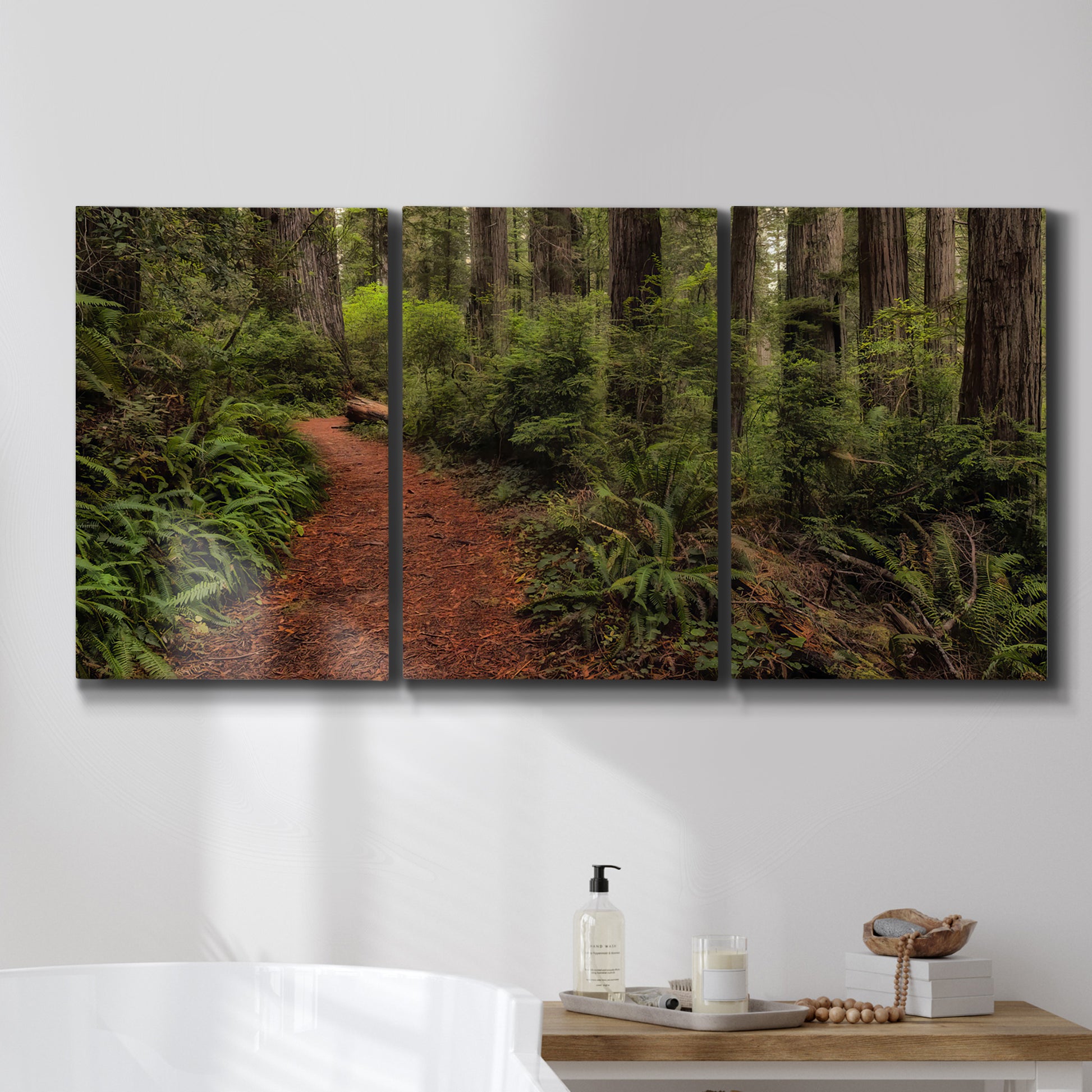 Three-panel canvas wall art featuring forest trail landscape photograph, displayed in a bathroom above a bathtub.