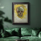 Expressive skull study painting by Vincent van Gogh in an ornate black frame with gilded inner detail displayed in a dark-toned interior setting.