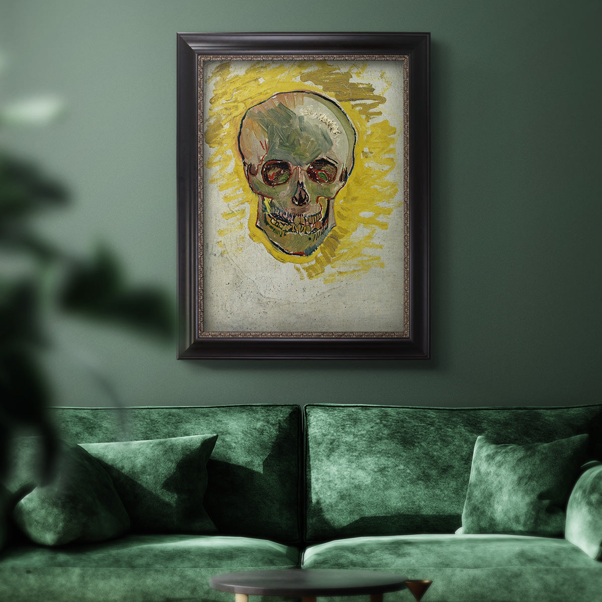 Expressive skull study painting by Vincent van Gogh in an ornate black frame with gilded inner detail displayed in a dark-toned interior setting.