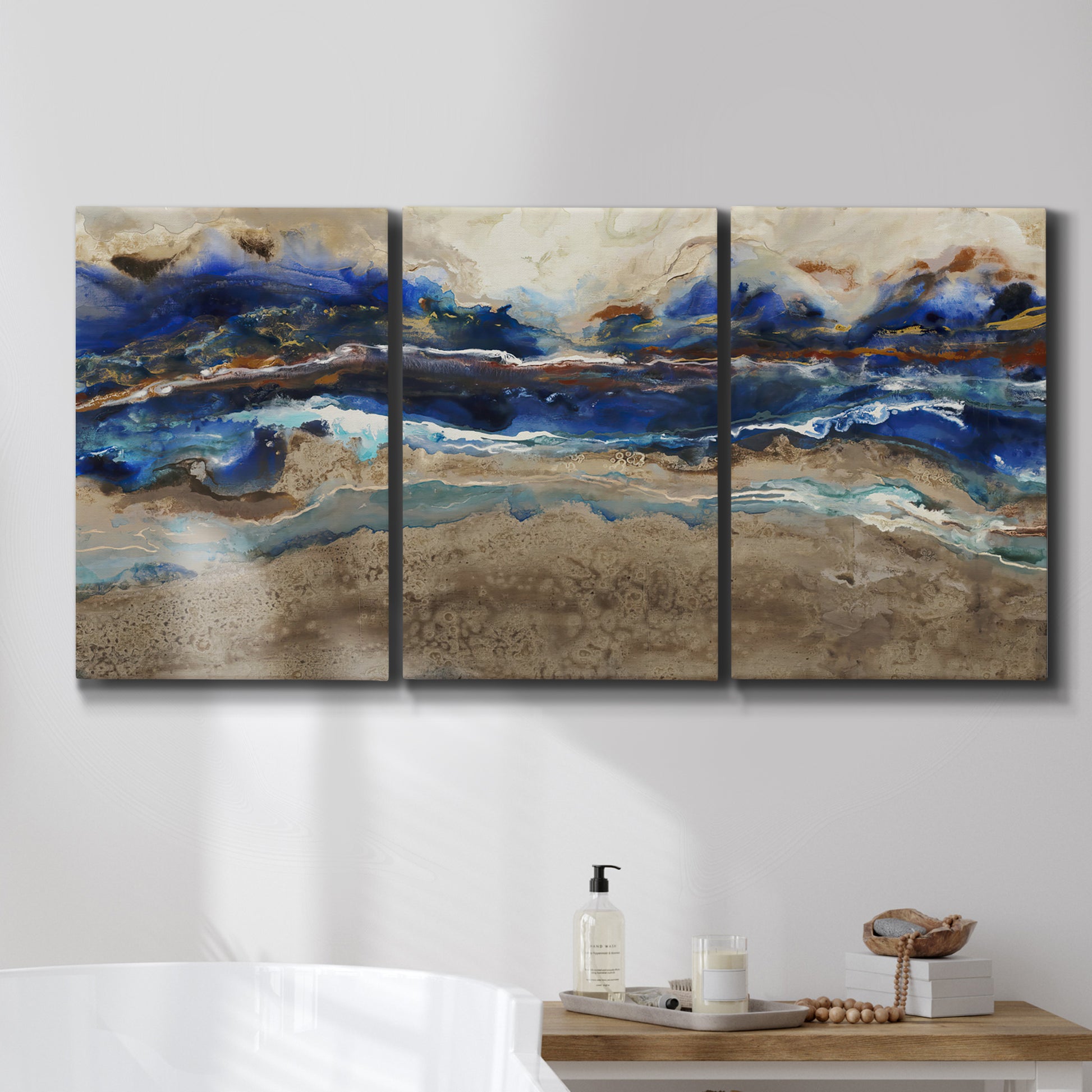 Three-panel canvas wall art featuring abstract coastal jewel toned composition, displayed in a bathroom above a bathtub.