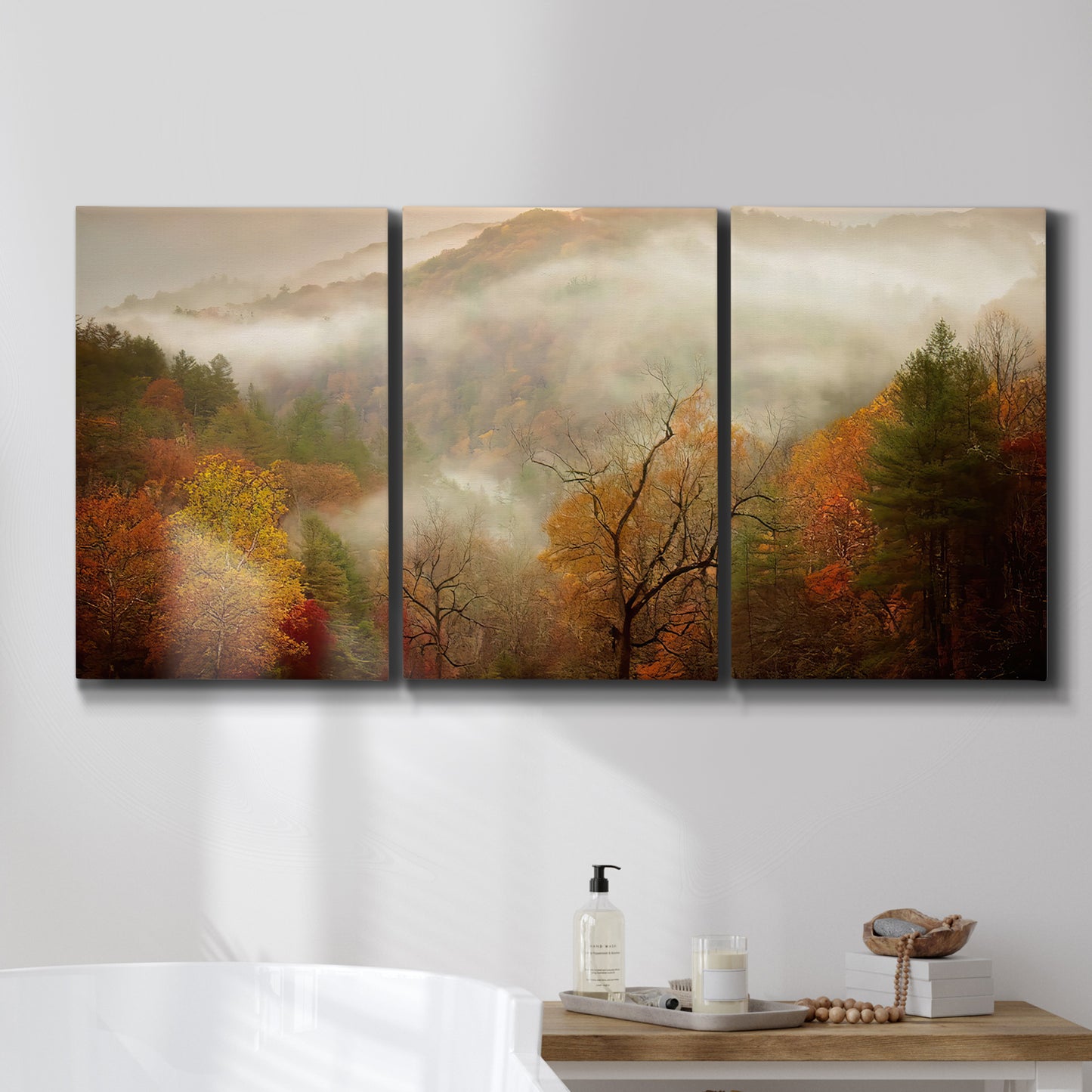 Three-panel canvas wall art featuring misty autumn landscape photograph, displayed in a bathroom above a bathtub.