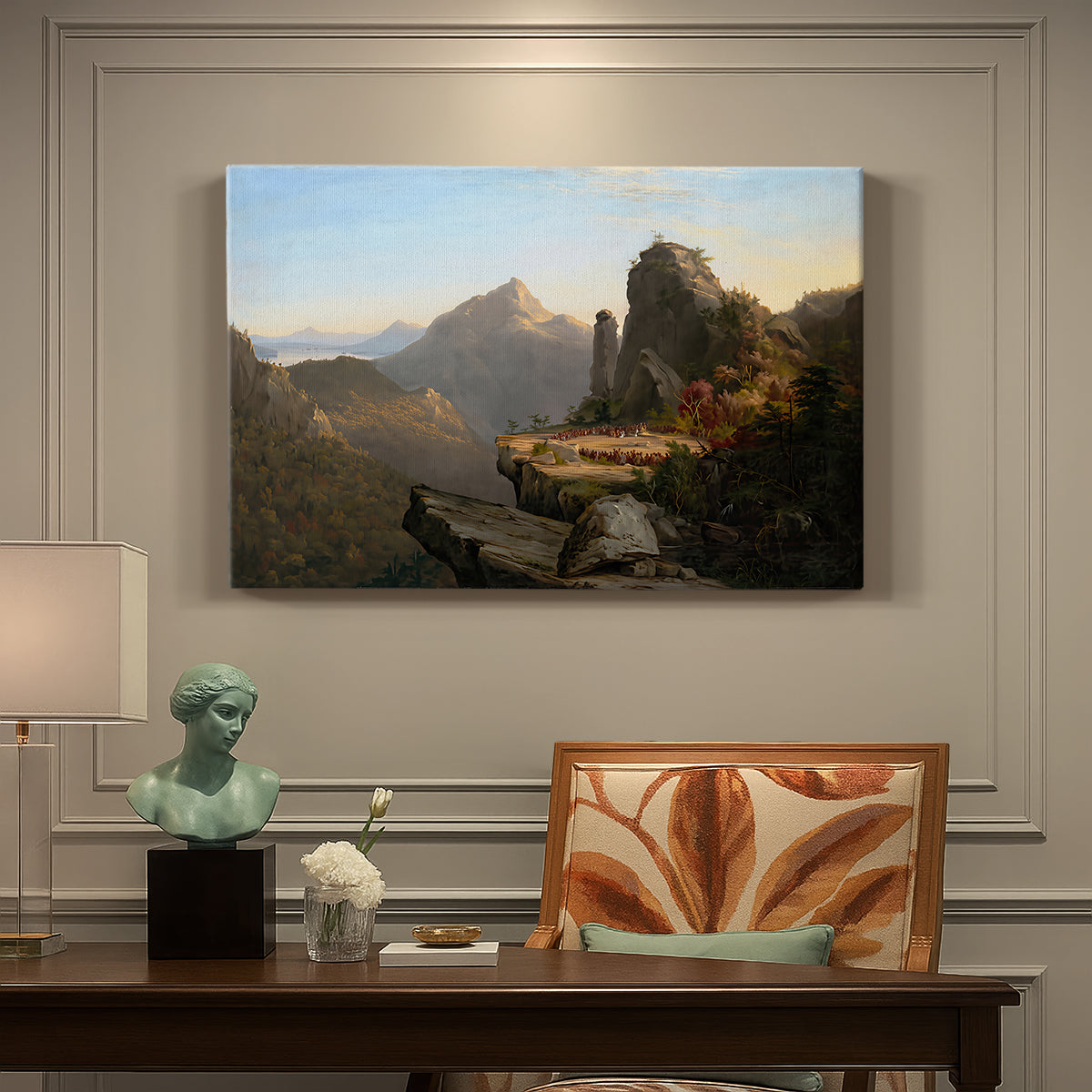 Canvas art print featuring a rugged mountain landscape with small figures near water and rocky cliffs, presented within a refined interior setting