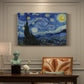 Canvas art print featuring a swirling night sky over village with bright stars, moon, and tall cypress, presented within a refined interior setting