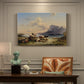 Canvas art print featuring shepherds tending cattle near lake with mountains, presented within a refined interior setting
