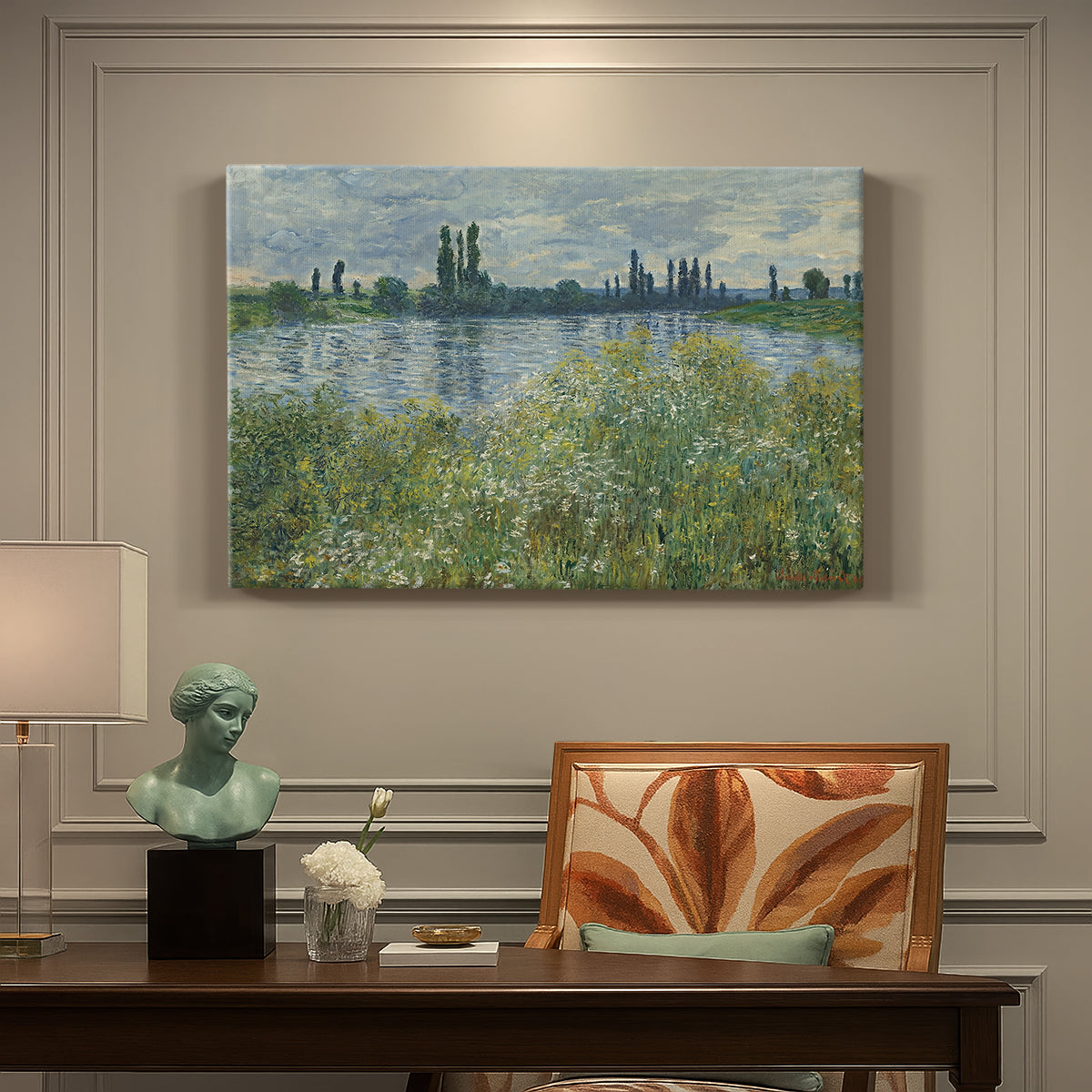 Canvas art print featuring a riverbank landscape with water, trees, and distant village buildings, presented within a refined interior setting