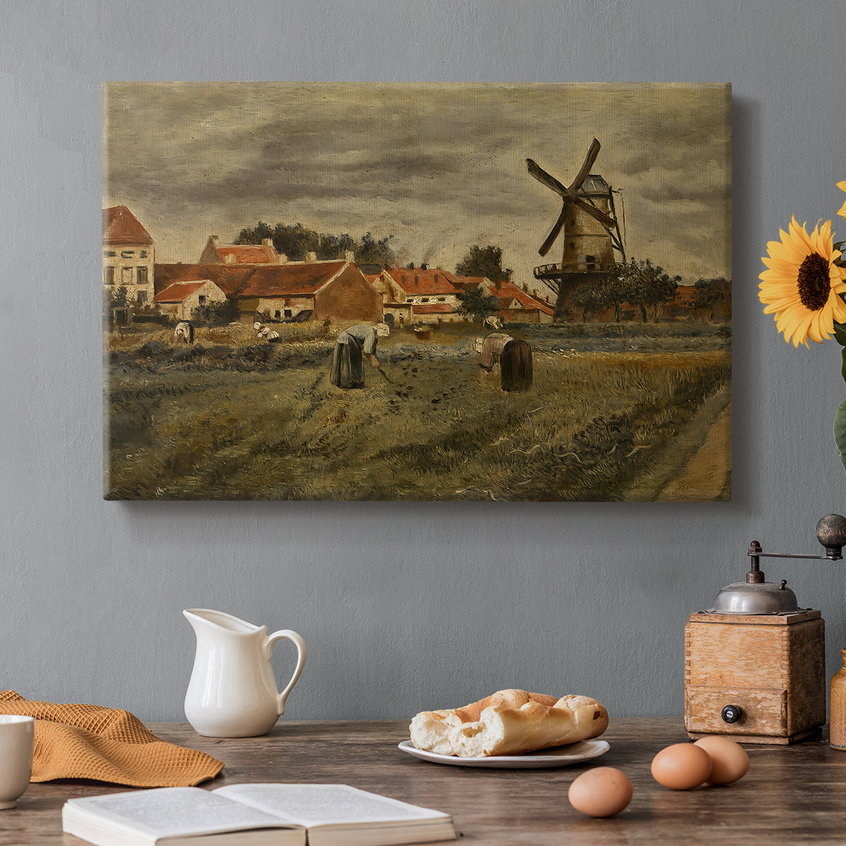 Canvas art print featuring a rural village scene with people working among buildings and open yard, set in a cozy kitchen setting