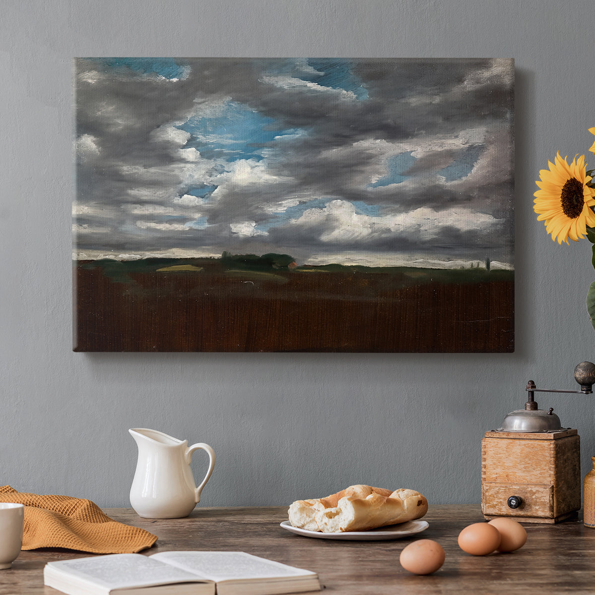 Canvas art print featuring a wide landscape beneath heavy grey clouds, set in a cozy kitchen setting