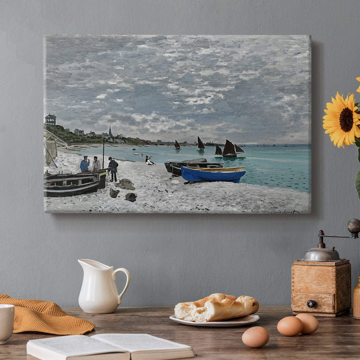 Canvas art print featuring a seaside promenade with figures, flags, and boats along the coast, set in a cozy kitchen setting
