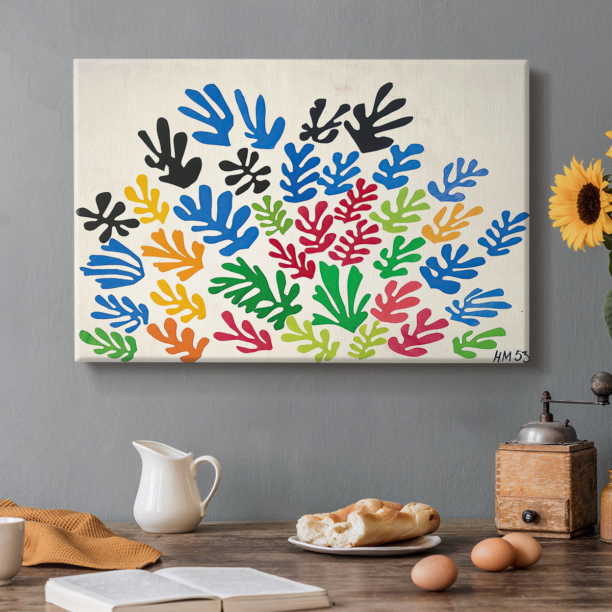 Canvas art print featuring an abstract arrangement of colorful leaf-like cut-outs, set in a cozy kitchen setting