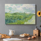 Canvas art print featuring a vivid green wheat field stretching across rolling landscape under pale sky, set in a cozy kitchen setting