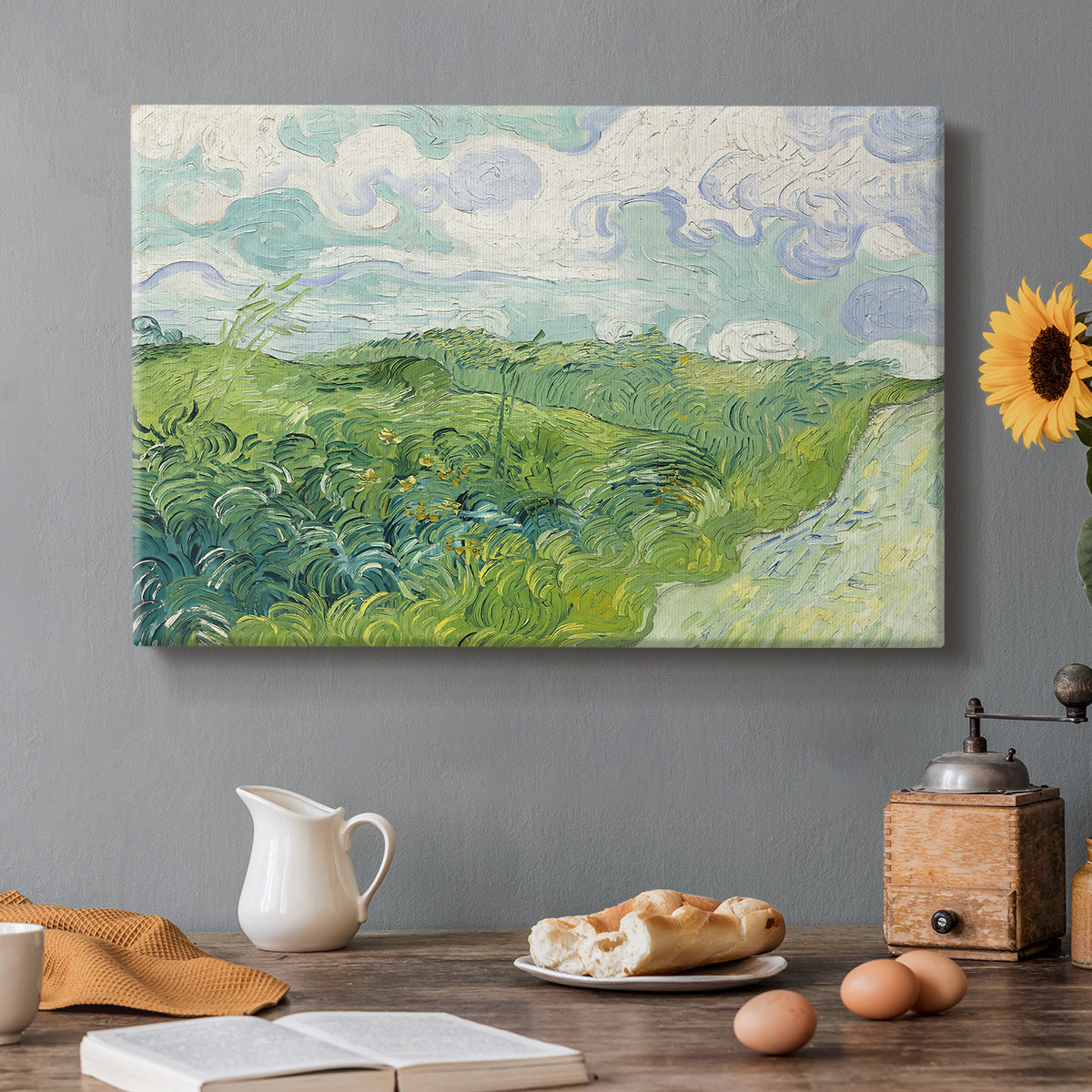 Canvas art print featuring a vivid green wheat field stretching across rolling landscape under pale sky, set in a cozy kitchen setting