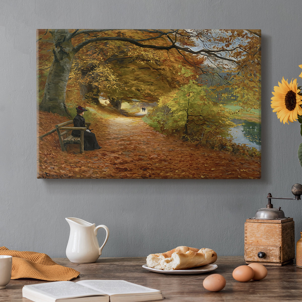 Canvas art print featuring figures walking along forest path covered in autumn leaves, set in a cozy kitchen setting
