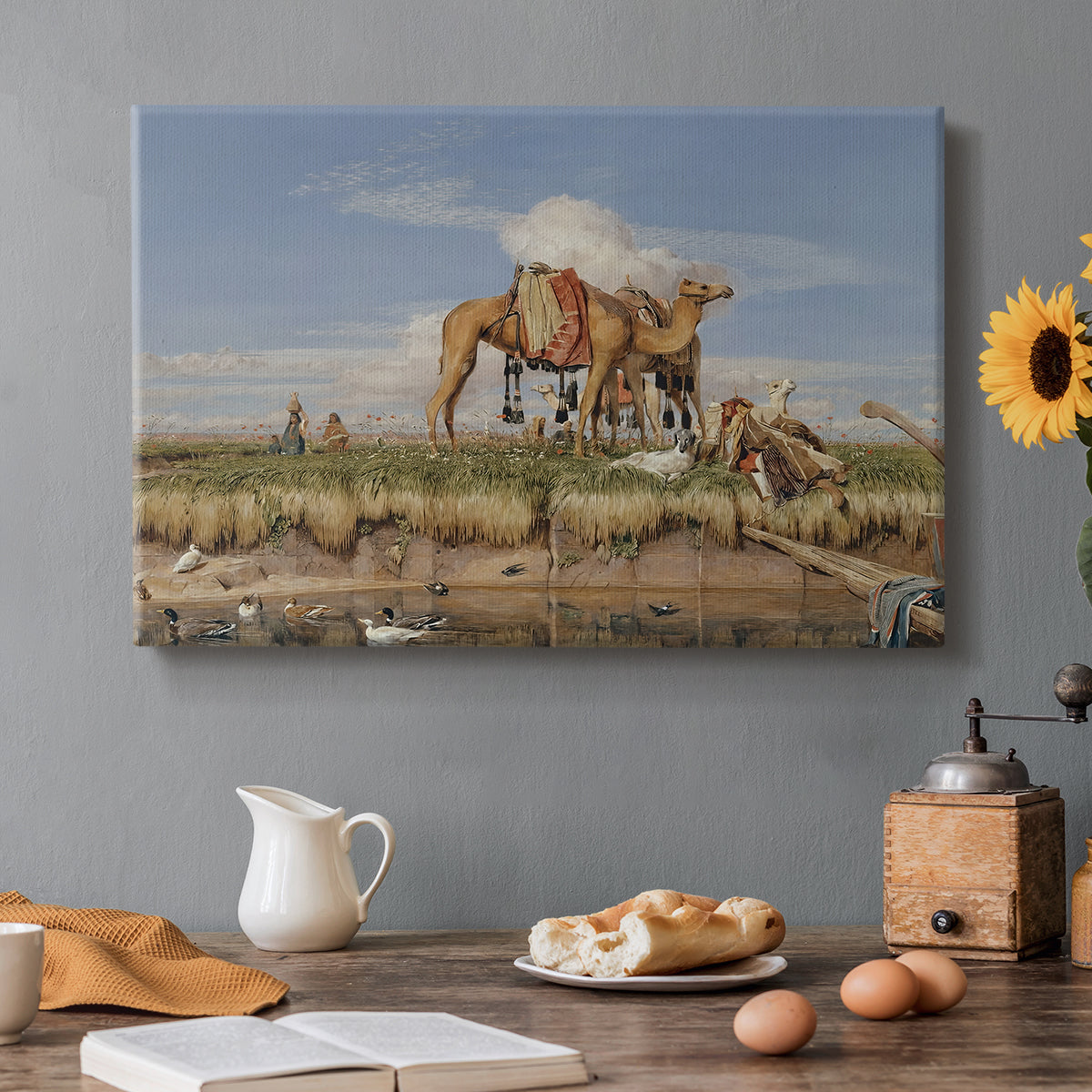 Canvas art print featuring figures and animals along riverbank with desert landscape, set in a cozy kitchen setting
