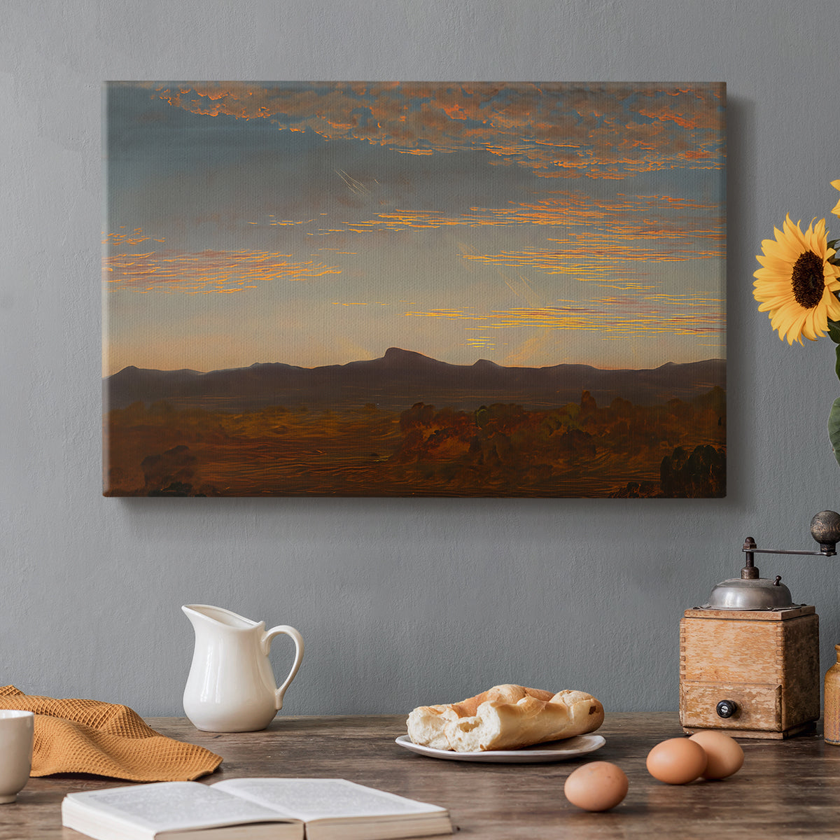 Canvas art print featuring a low mountain landscape under warm sky with broad open foreground, set in a cozy kitchen setting