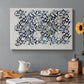 Canvas art print featuring a repeating floral design with flowing stems and scattered blossoms across light background, set in a cozy kitchen setting