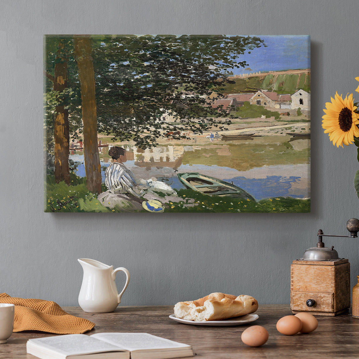 Canvas art print featuring a woman and child seated along riverbank beneath trees in soft daylight, set in a cozy kitchen setting