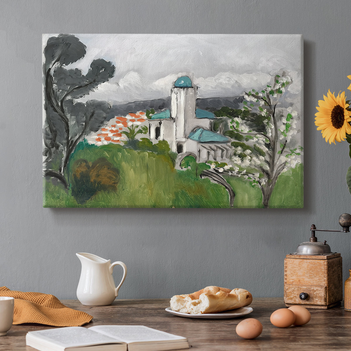 Canvas art print featuring a blue villa surrounded by trees and greenery in a bright landscape, set in a cozy kitchen setting