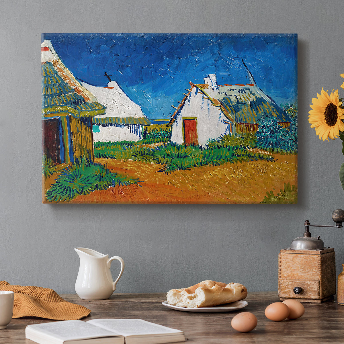 Canvas art print featuring white cottages grouped together with bold colors and surrounding landscape, set in a cozy kitchen setting