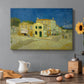Canvas art print featuring a street view with bright yellow house and neighboring buildings under blue sky, set in a cozy kitchen setting