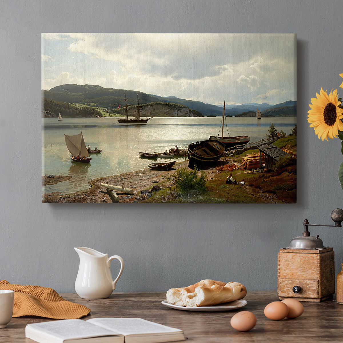 Canvas art print featuring figures and boats gathered along shoreline in calm coastal setting, set in a cozy kitchen setting