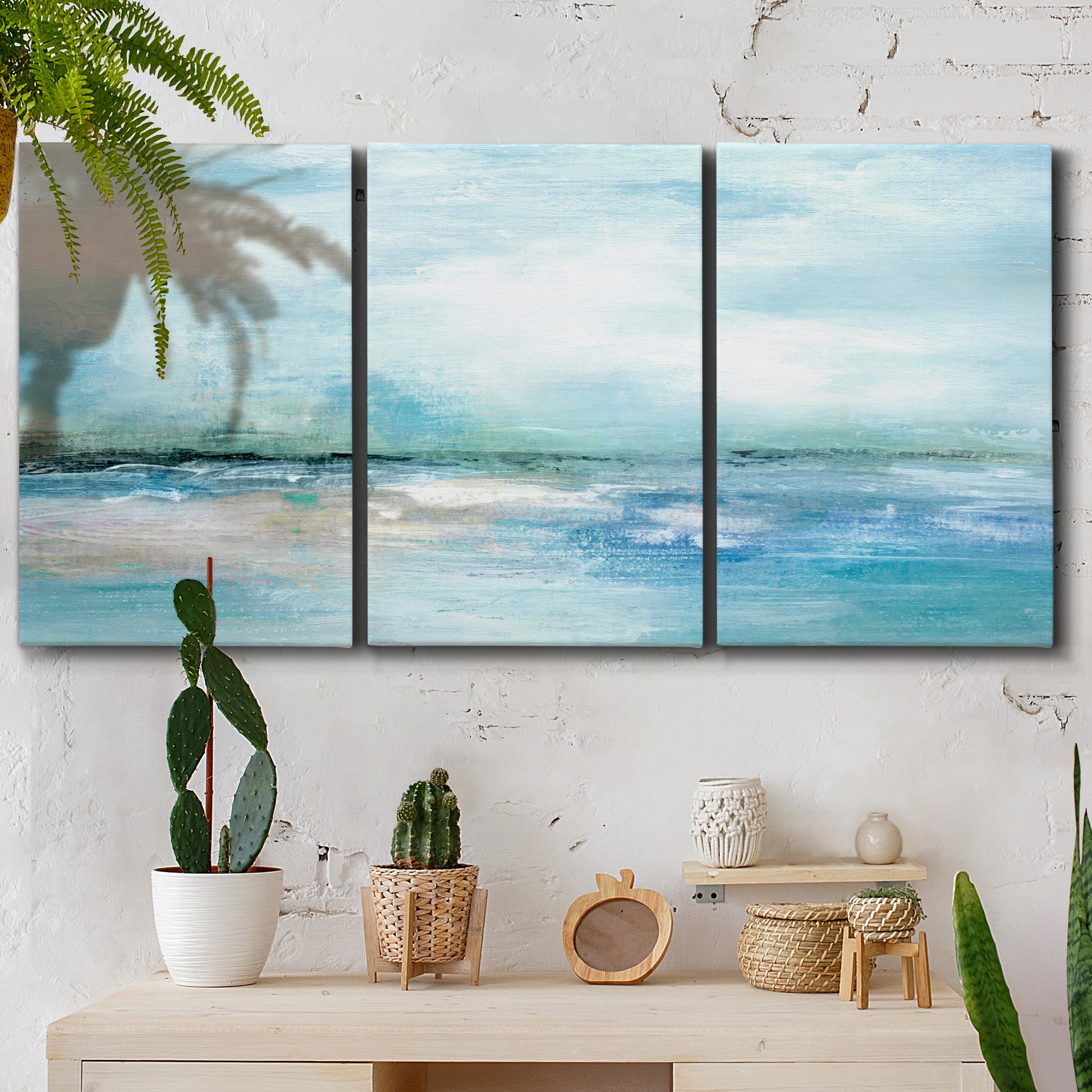 Three-panel canvas wall art featuring sunset silhouette over coastal water, displayed in a boho-chic entryway above a console table.