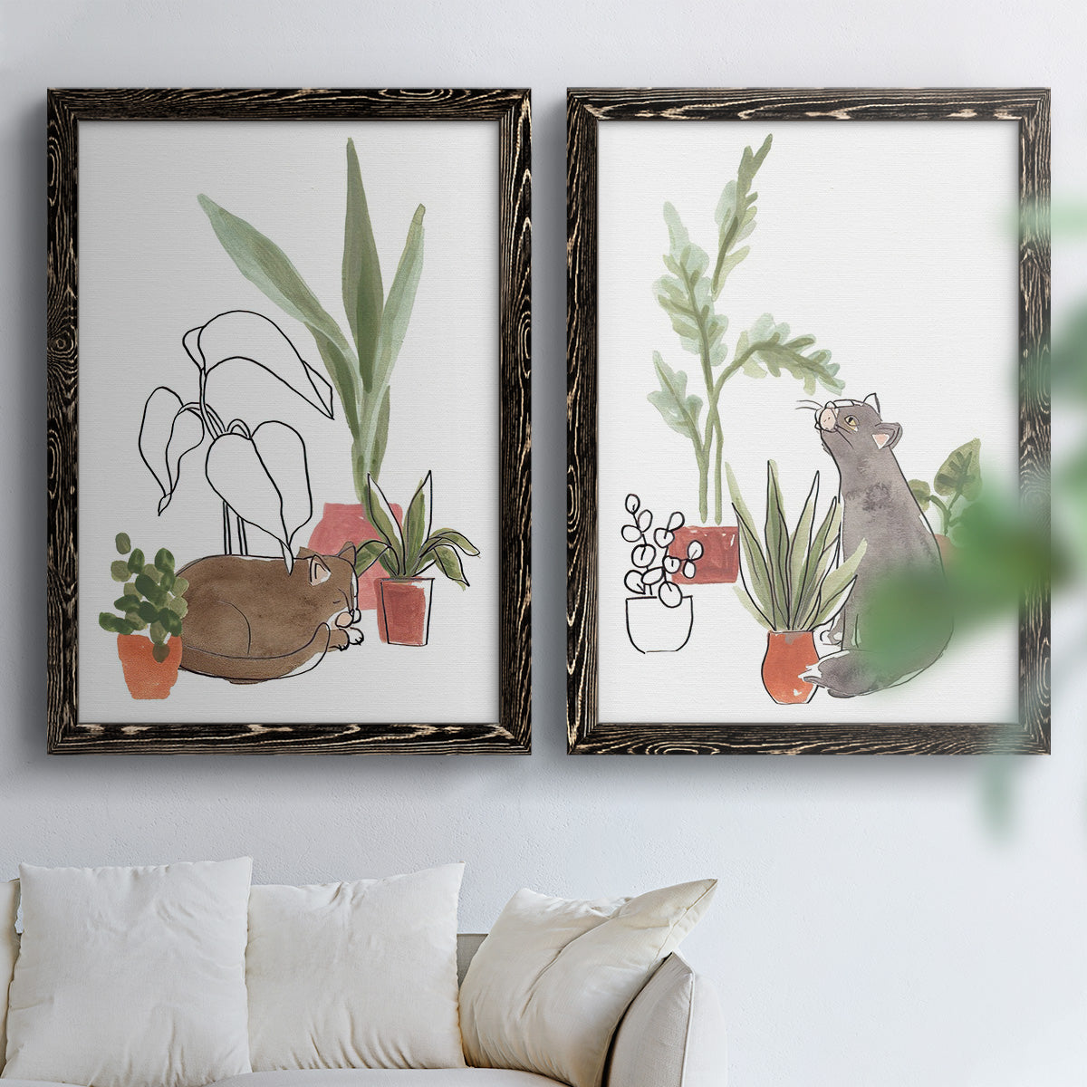 Set of two black barnwood framed canvas prints depicting curious felines, terracotta pots, succulents, and leafy stems arranged across two complementary compositions above a sofa in a bright living space.