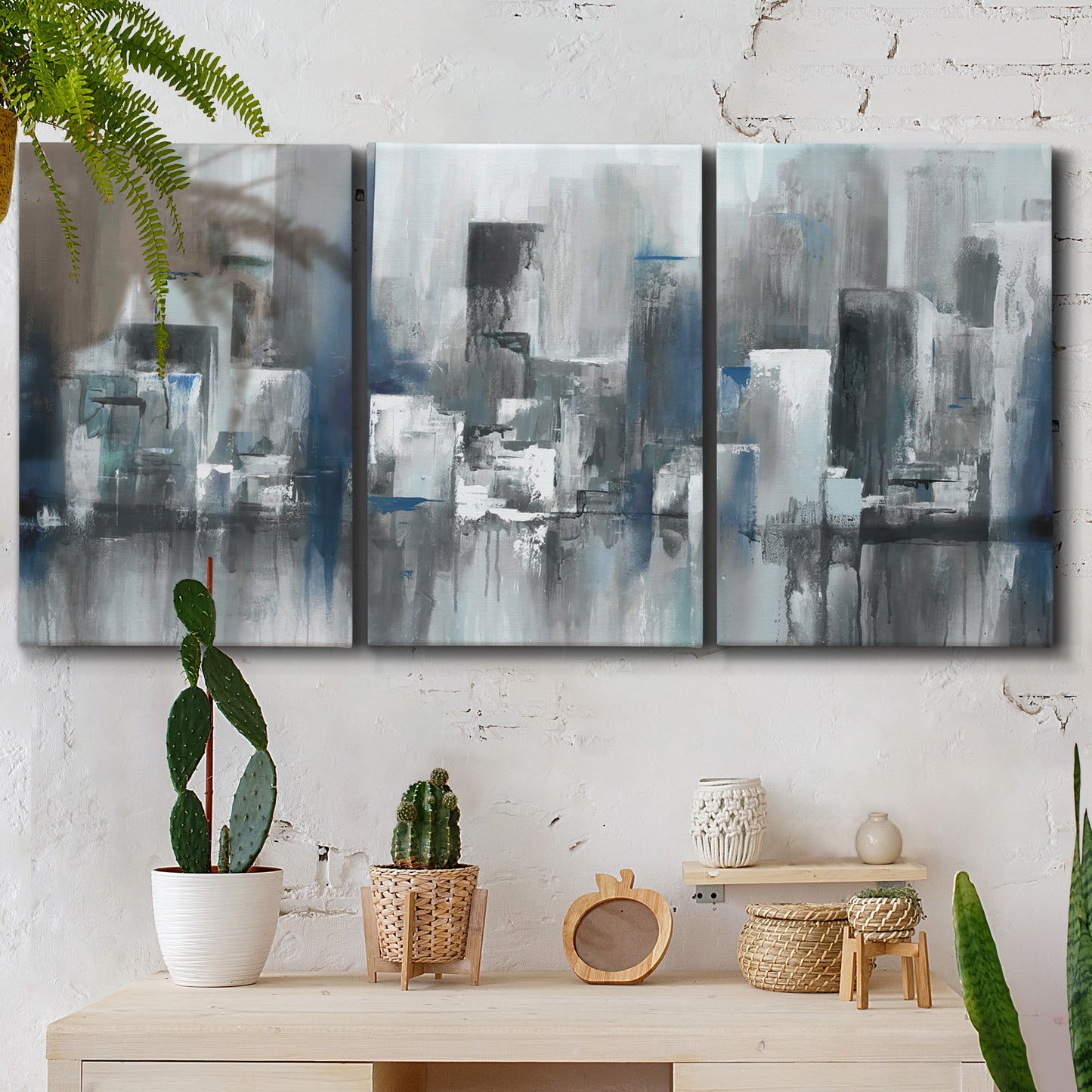 Three-panel canvas wall art featuring urban cityscape rendered in blue tones, displayed in a boho-chic entryway above a console table.