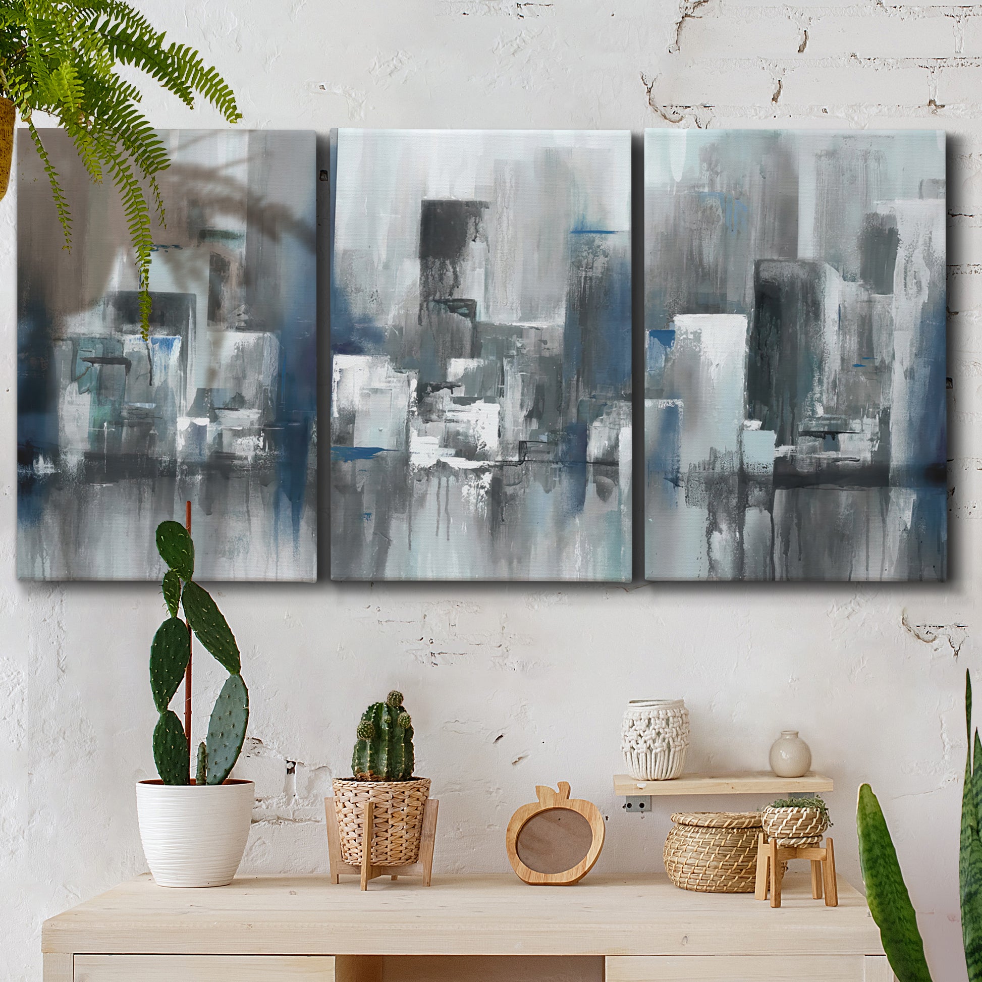 Three-panel canvas wall art featuring urban cityscape rendered in blue tones, displayed in a boho-chic entryway above a console table.
