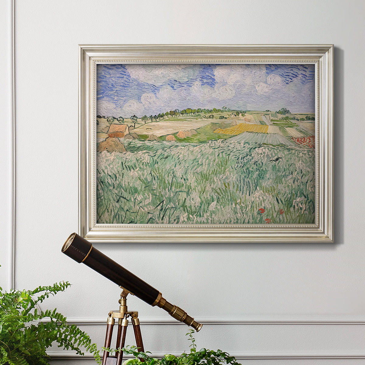Impressionist countryside landscape near Auvers by Vincent van Gogh in an ornate champagne frame displayed in a light-toned interior setting.