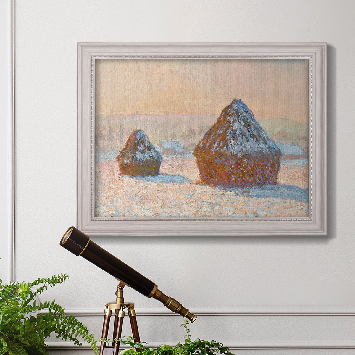 Impressionist winter haystack scene by Claude Monet in an ornate weathered white frame displayed in a light-toned interior setting.