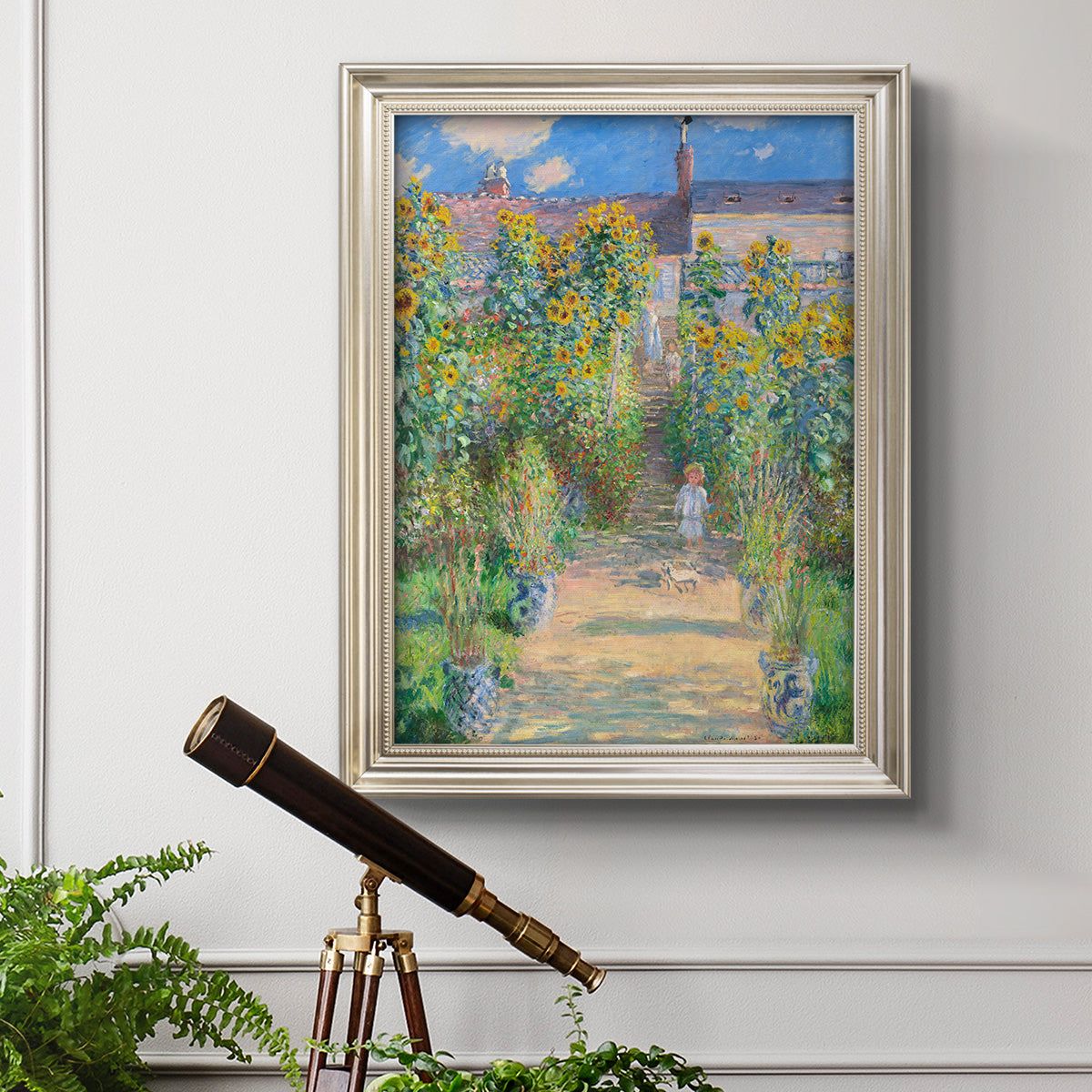 Impressionist garden landscape painting by Claude Monet in an ornate champagne frame displayed in a light-toned interior setting.
