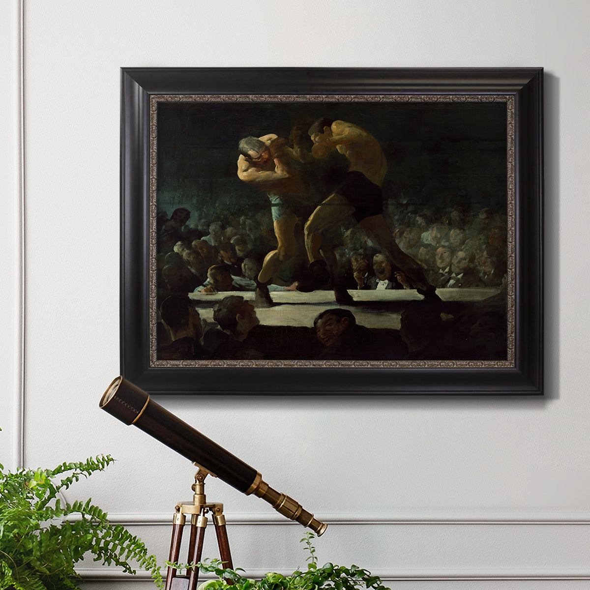 American social club scene painting by George Bellows in an ornate black frame with gilded inner detail displayed in a light-toned interior setting.