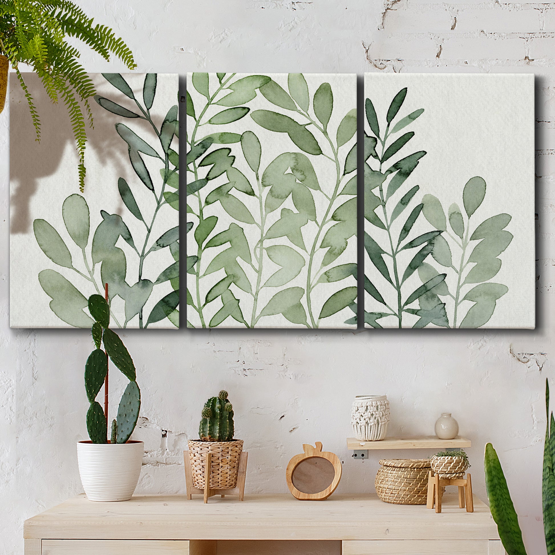 Three-panel canvas wall art featuring foraged leafy greens botanical study, displayed in a boho-chic entryway above a console table.
