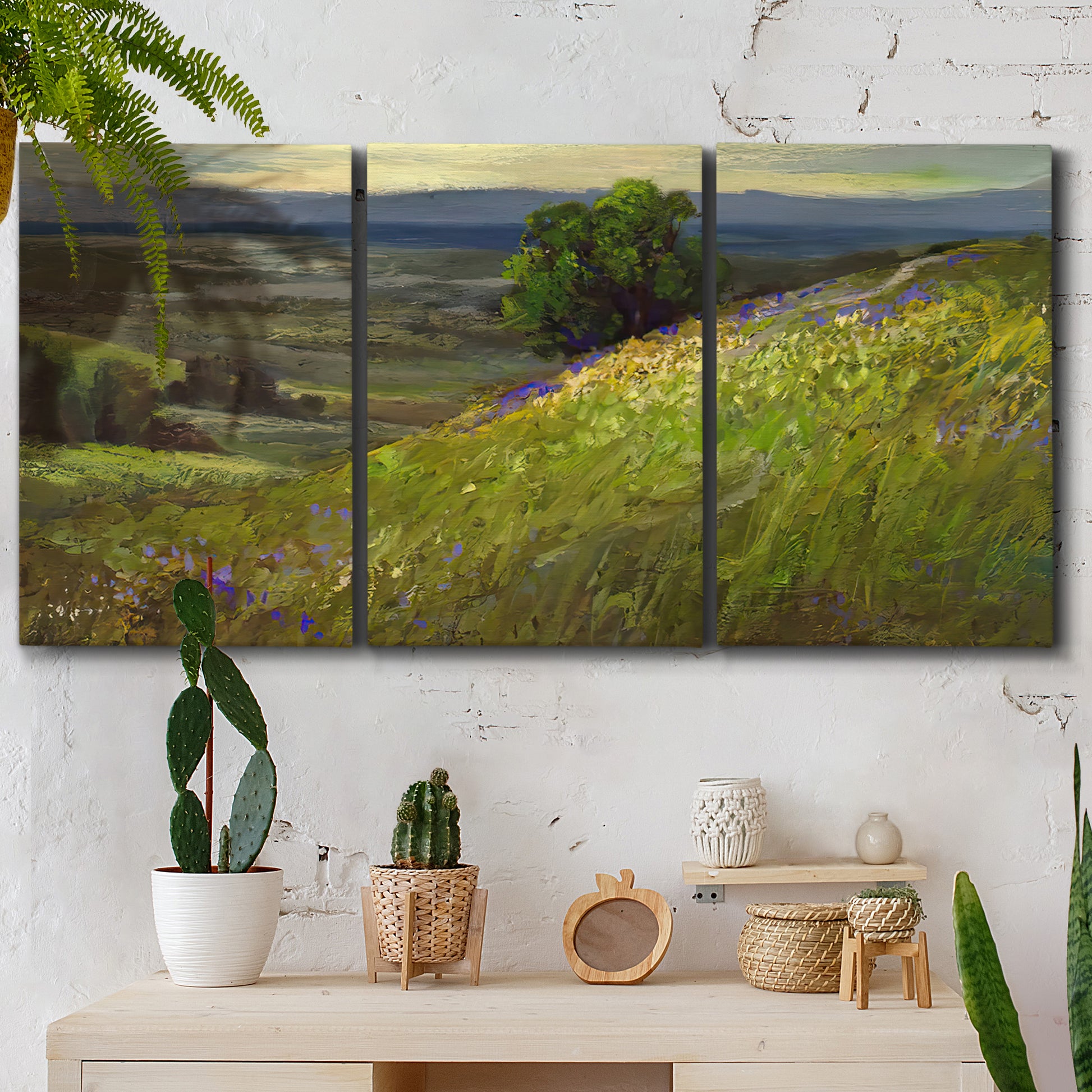 Three-panel canvas wall art featuring winding path through rolling hills, displayed in a boho-chic entryway above a console table.