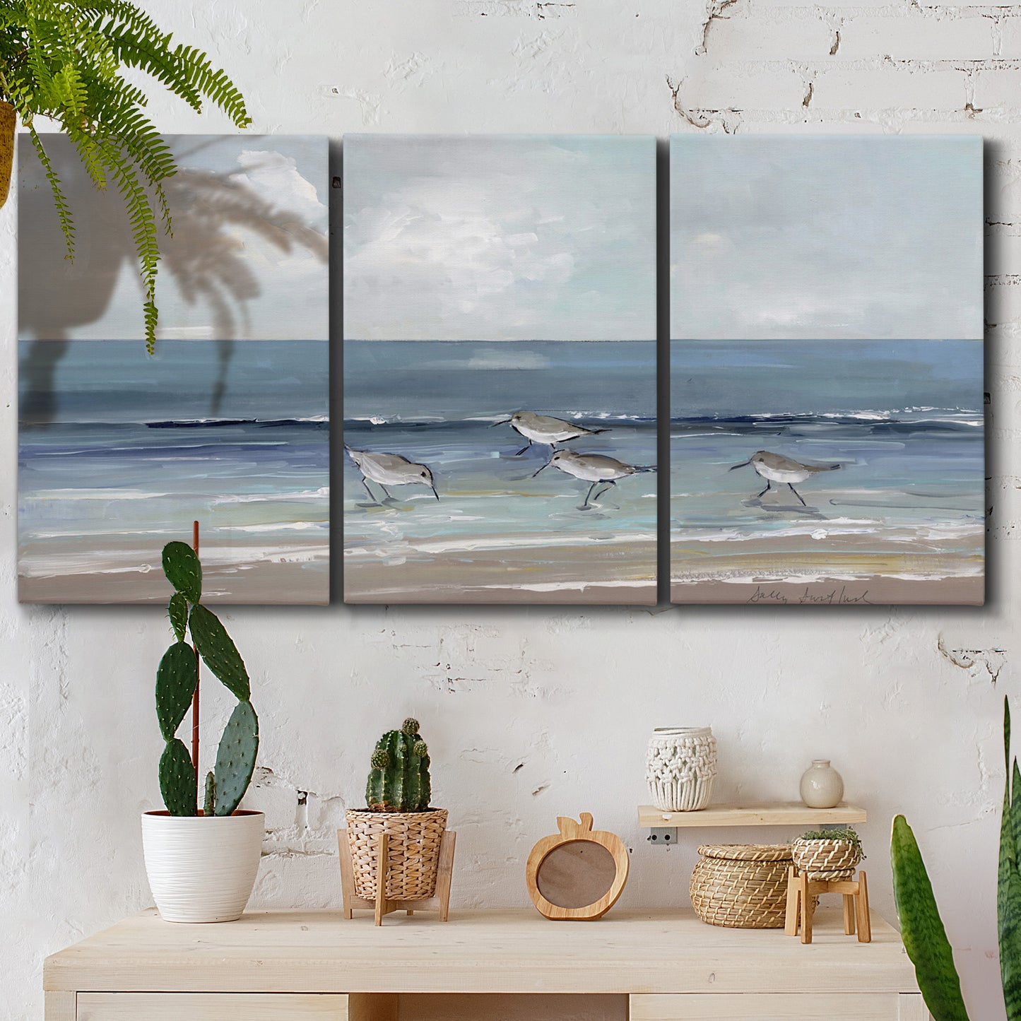 Three-panel canvas wall art featuring shore birds searching along beach, displayed in a boho-chic entryway above a console table.