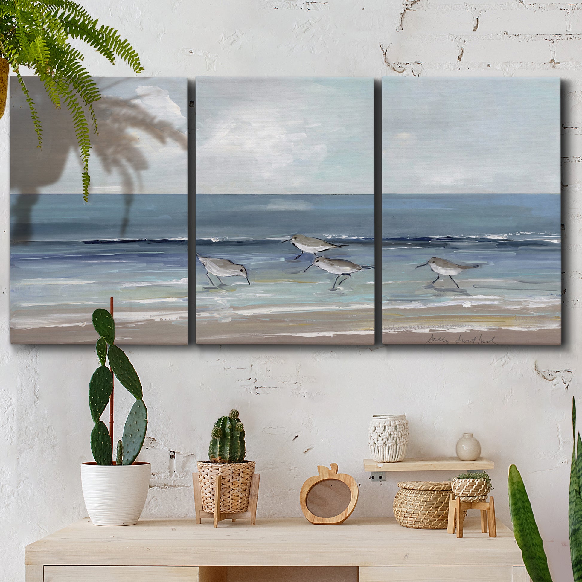 Three-panel canvas wall art featuring shore birds searching along beach, displayed in a boho-chic entryway above a console table.