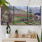 Three-panel canvas wall art featuring cliffside cottage overlooking sea, displayed in a boho-chic entryway above a console table.
