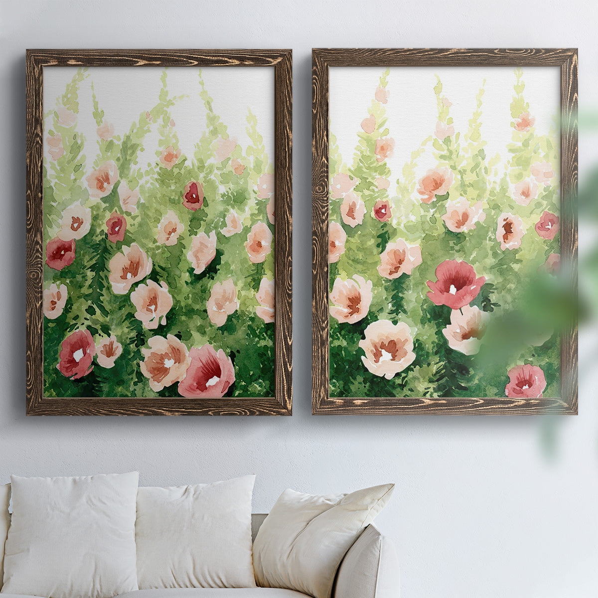 Set of two walnut barnwood framed canvas prints depicting loose blossoms, green stems, and sunlit watercolor texture arranged across two complementary compositions above a sofa in a bright living space.