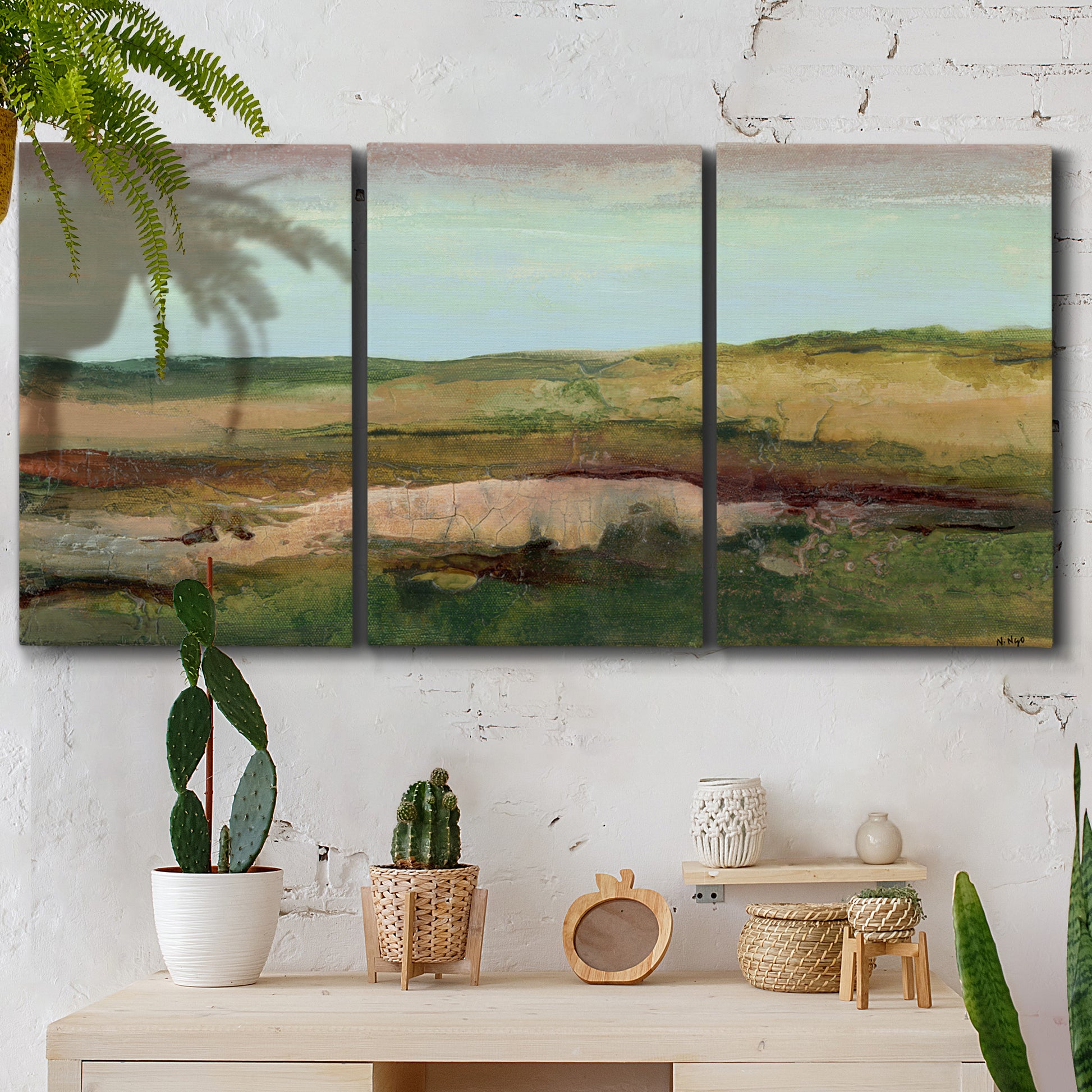 Three-panel canvas wall art featuring pastoral landscape with winding road, displayed in a boho-chic entryway above a console table.