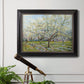 Impressionist white-blossomed orchard landscape by Vincent van Gogh in an ornate black frame with gilded inner detail displayed in a light-toned interior setting.