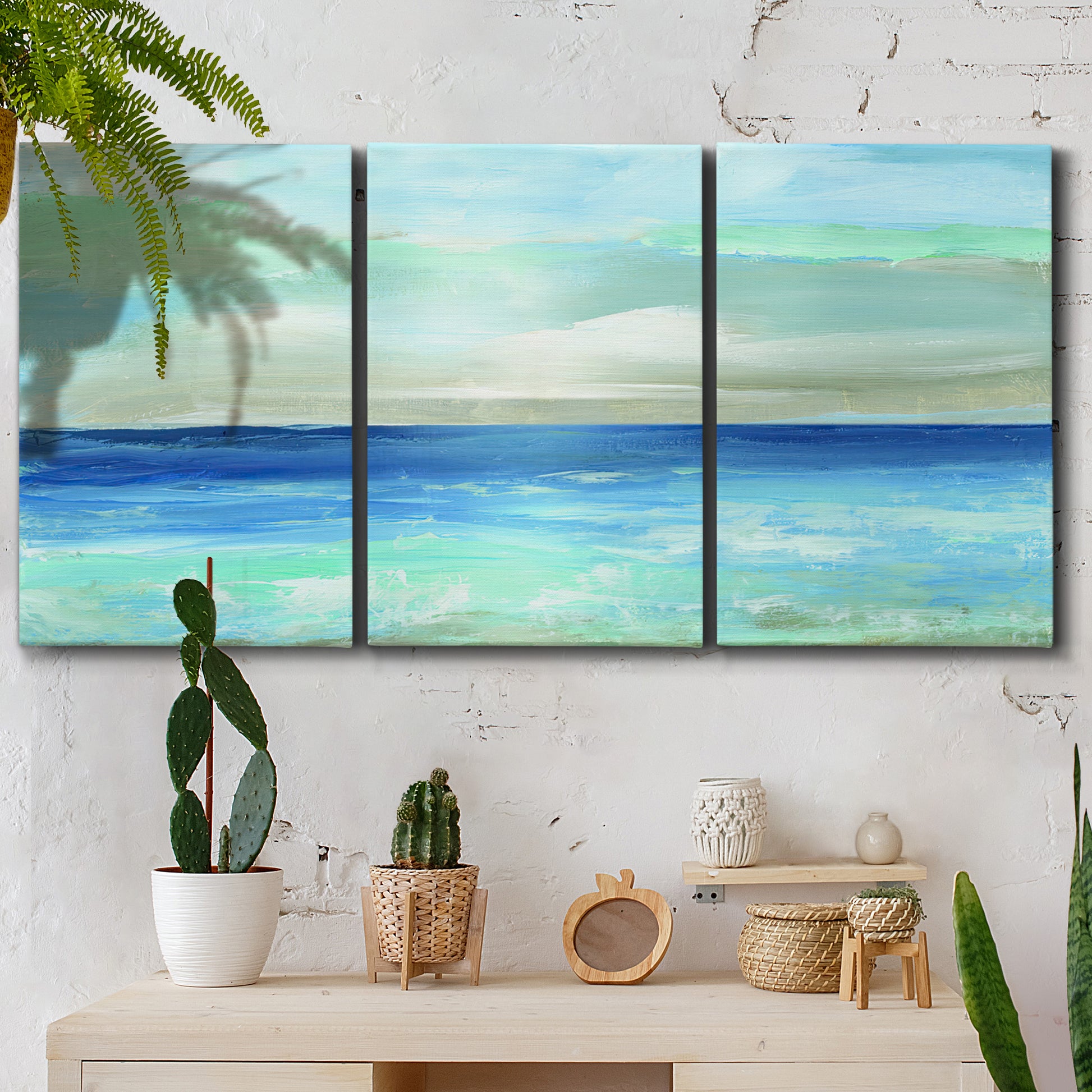 Three-panel canvas wall art featuring vast open blue ocean horizon, displayed in a boho-chic entryway above a console table.