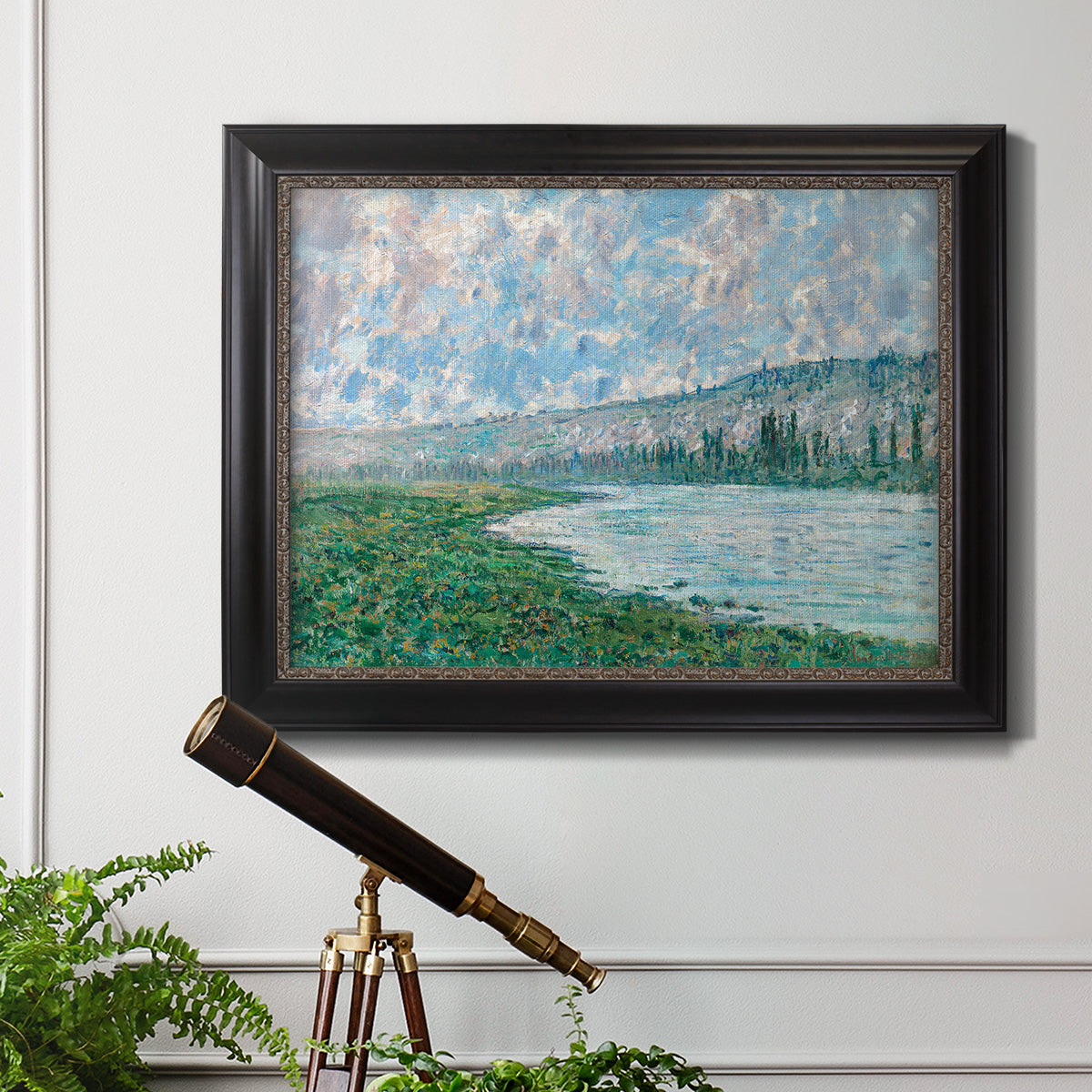 Impressionist river landscape at Vétheuil by Claude Monet in an ornate black frame with gilded inner detail displayed in a light-toned interior setting.