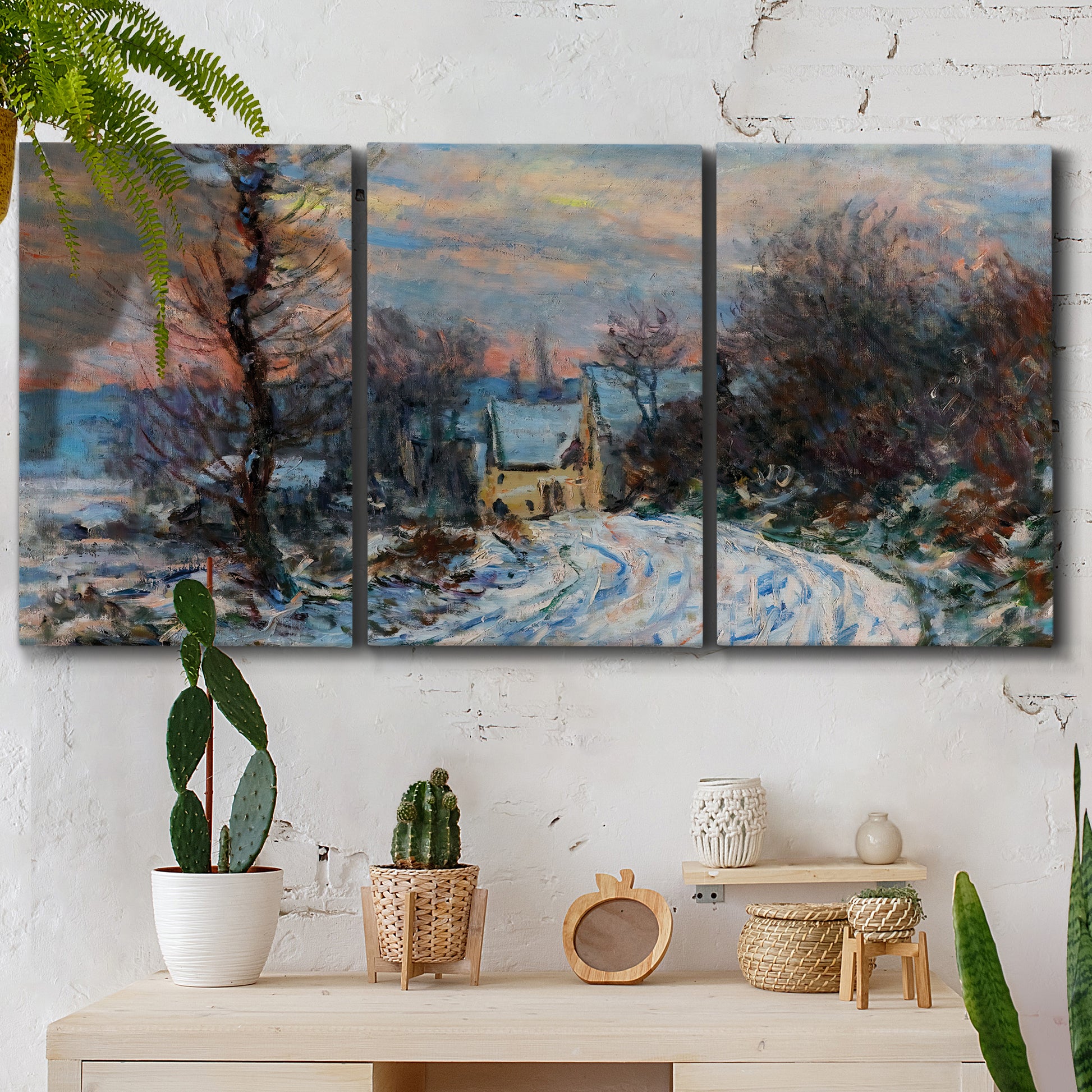 Three-panel canvas wall art featuring snow covered road leading to village, displayed in a boho-chic entryway above a console table.