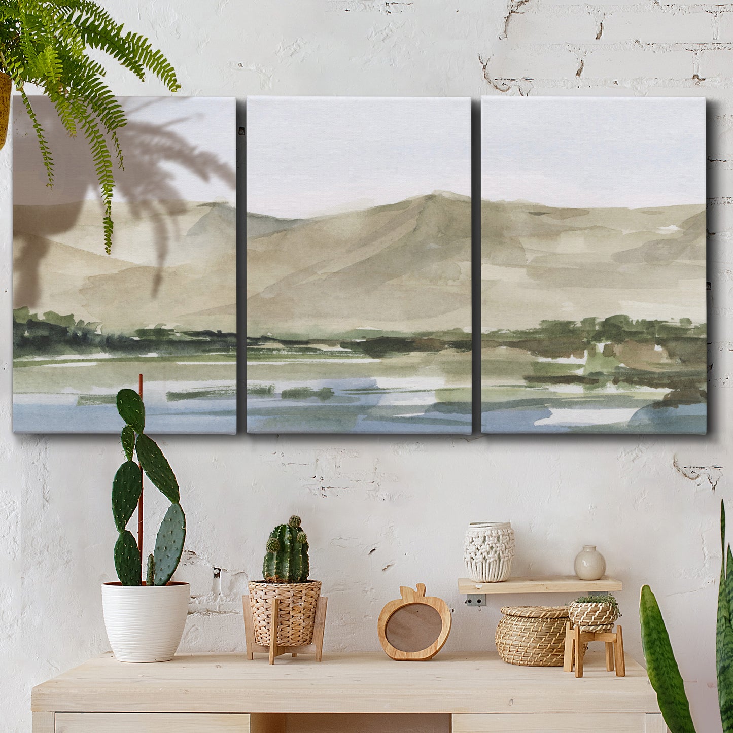 Three-panel canvas wall art featuring desert mountain landscape watercolor, displayed in a boho-chic entryway above a console table.