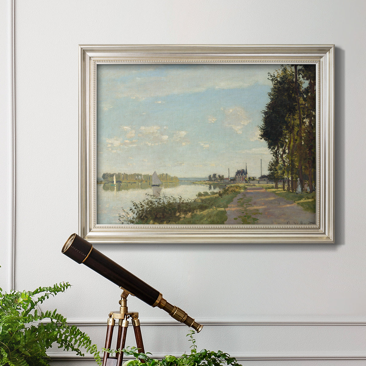 Impressionist river scene with red boats by Claude Monet in an ornate champagne frame displayed in a light-toned interior setting.
