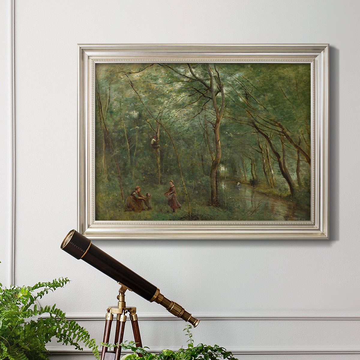 Traditional rural landscape scene with figures by Jean-Baptiste-Camille Corot in an ornate champagne frame displayed in a light-toned interior setting.
