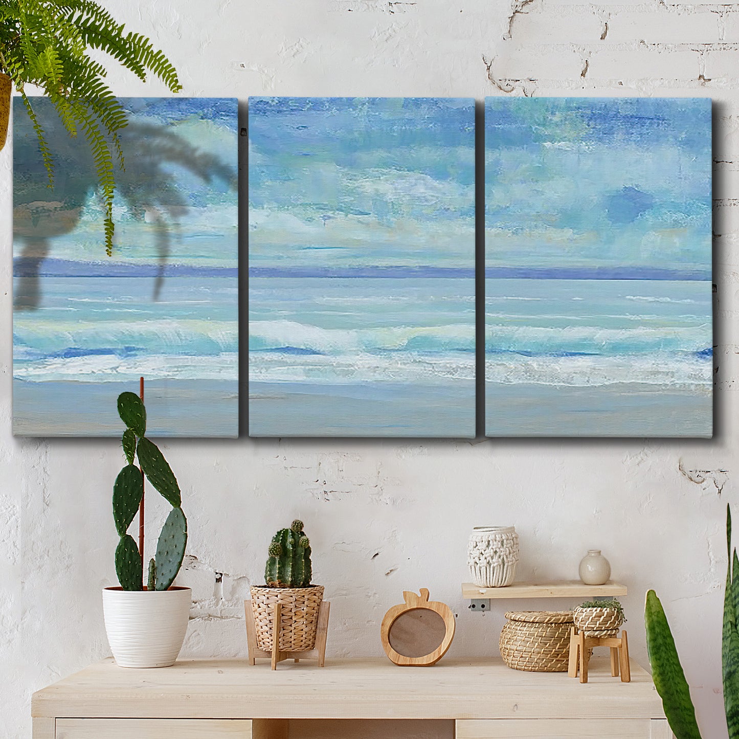 Three-panel canvas wall art featuring rolling ocean surf along shoreline, displayed in a boho-chic entryway above a console table.